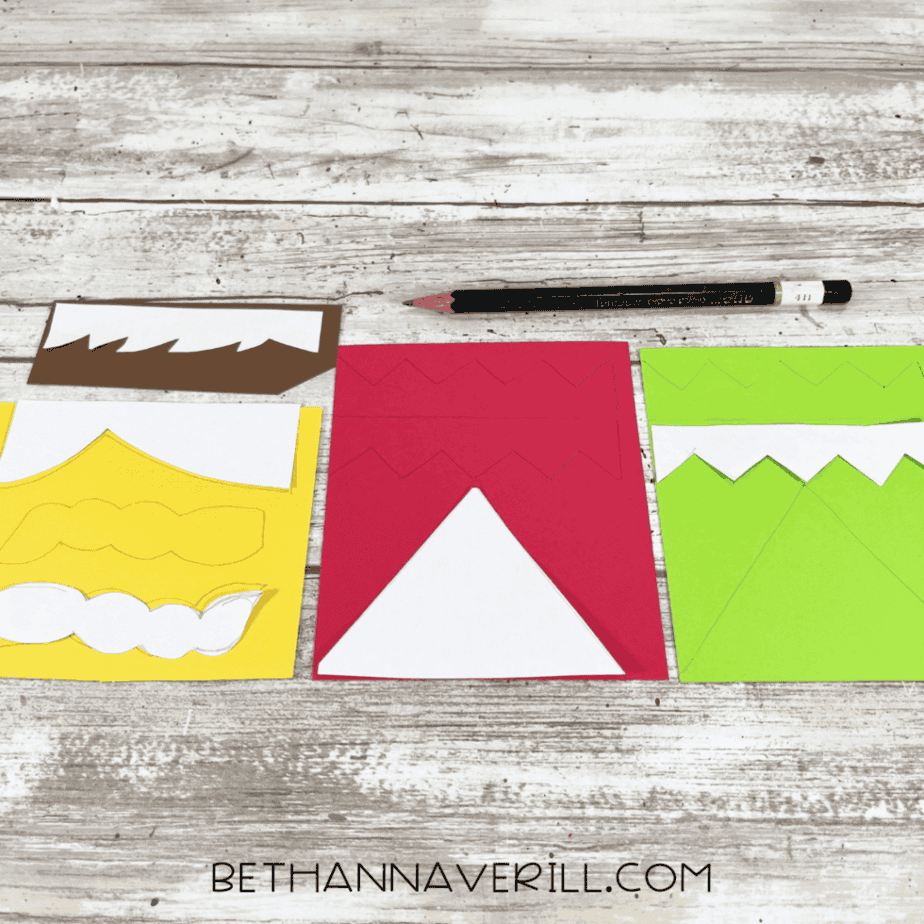 Cardstock pattern pieces for elf hats, collars, hair, and trim laid out on a white wood surface with a pencil above them.