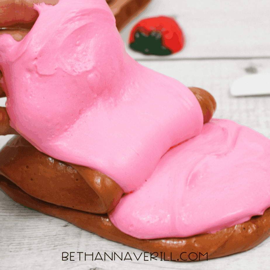 Pink fluffy slime being pressed on top of brown fluffy slime on a tabletop.