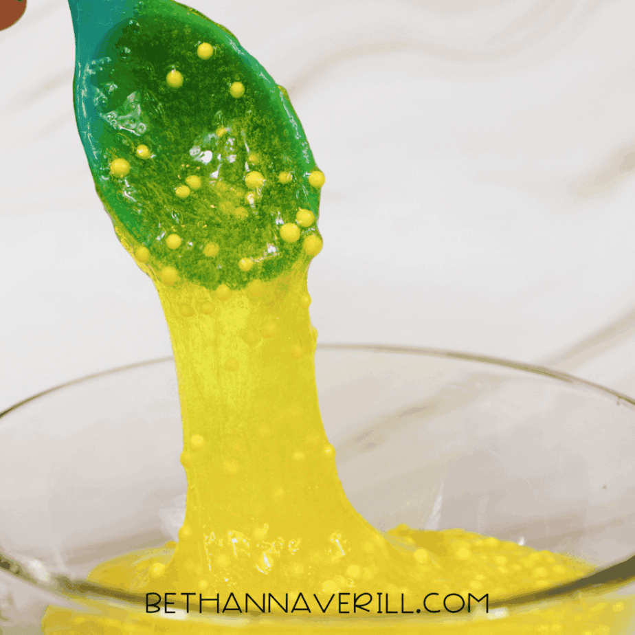 Yellow lemonade slime forming as ingredients combine, with foam beads suspended throughout.