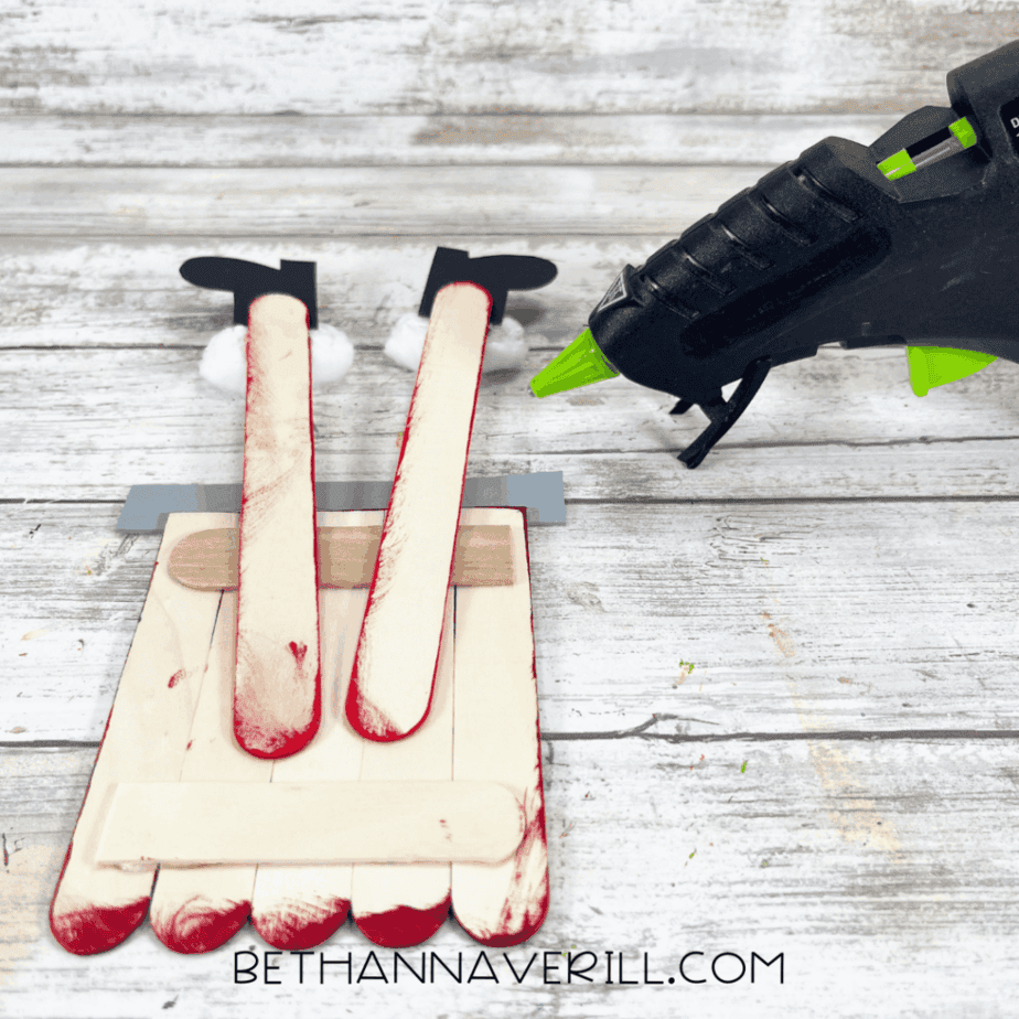 Attaching Santa legs to popsicle stick chimney base using hot glue