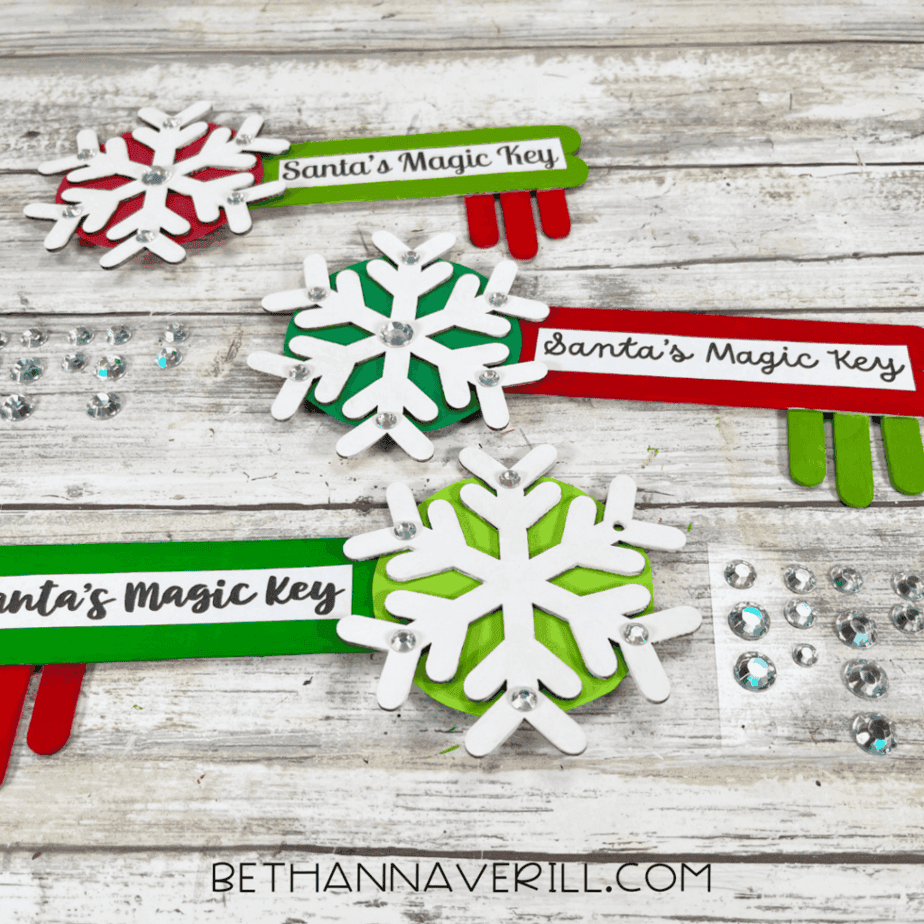 Santa Magic Key popsicle stick crafts decorated with white snowflakes, rhinestones, and red and green painted wooden keys.