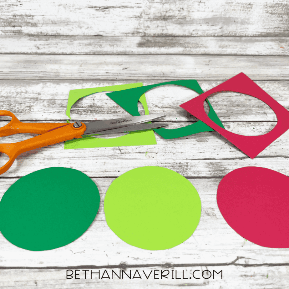 Cut cardstock circles in red and green laid out on a table after trimming for the Santa Magic Key craft.