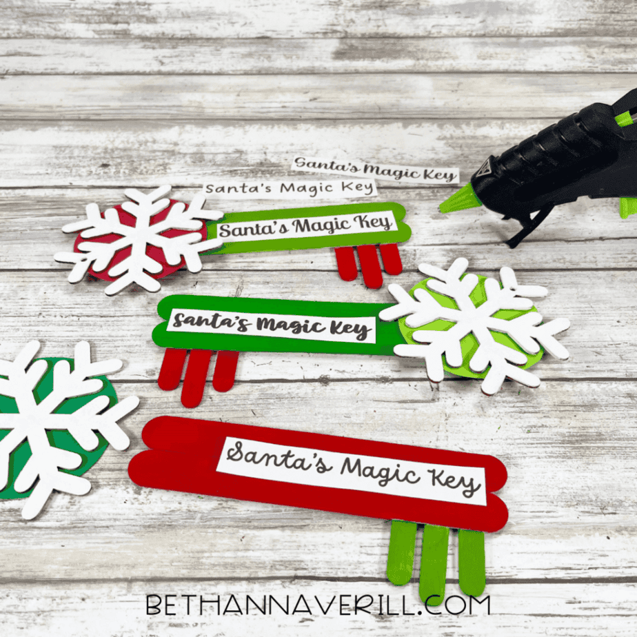 Completed Santa Magic Key popsicle stick crafts with snowflake decorations, labels attached, and keys fully assembled.