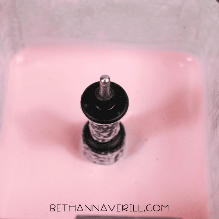 Pink-tinted aquafaba whipping inside a blender, creating a light and foamy texture.