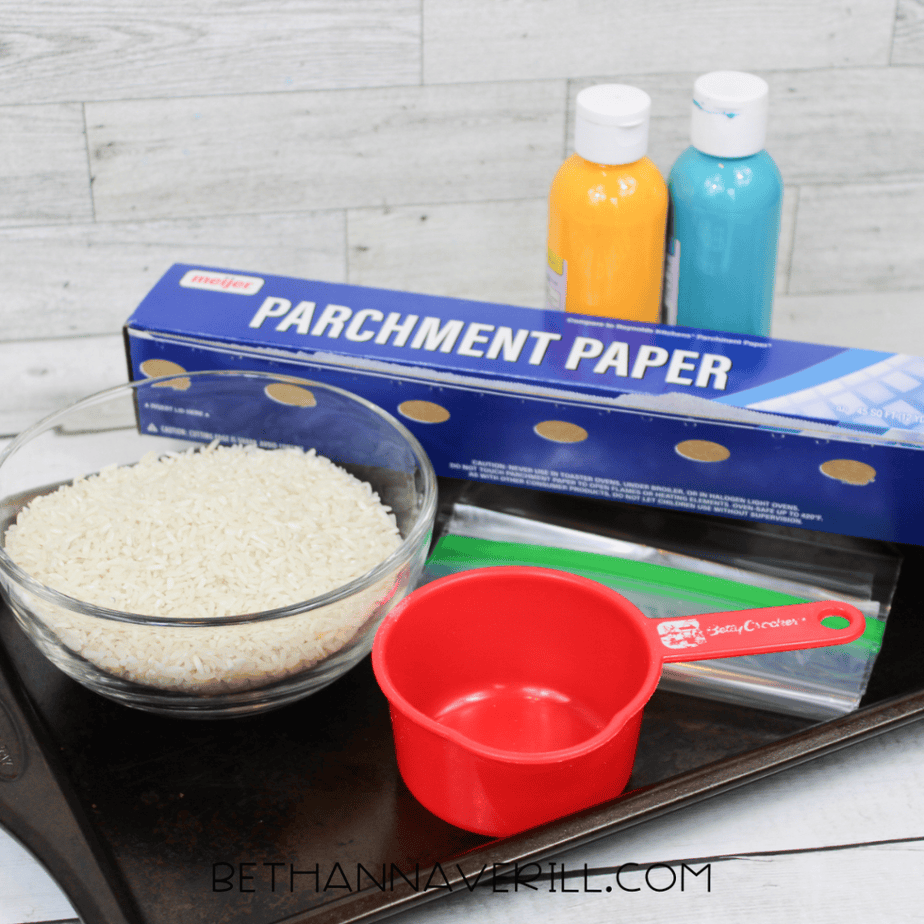 Supplies for spring sensory bottle including rice, food coloring, ziplock bags, parchment paper, and clear bottle