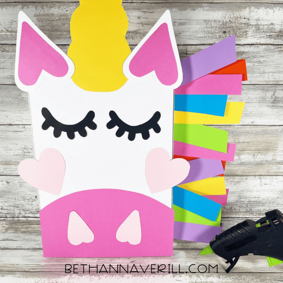Nearly finished unicorn box with rainbow paper mane attached to one side and facial features glued in place.