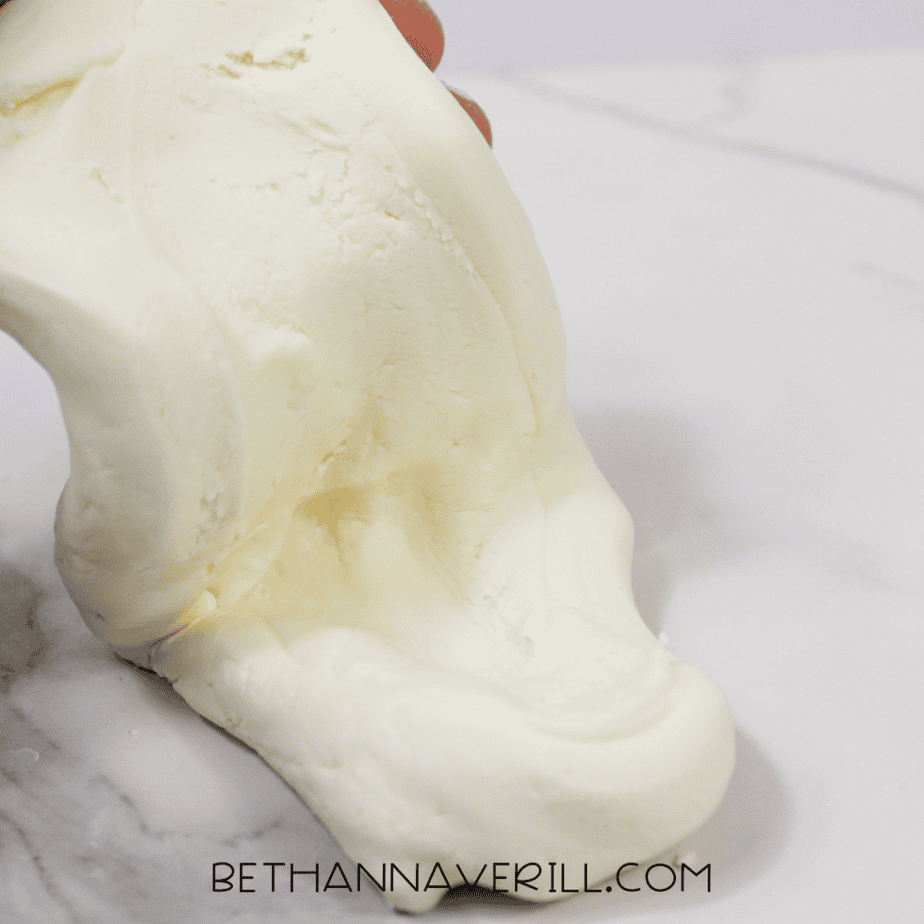 Close-up of white slime stretching downward in a soft, glossy fold.