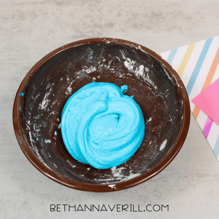 A smooth ball of bright blue slime resting inside a brown mixing bowl.