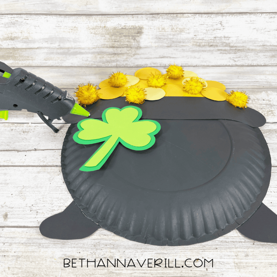 Image of a layered green shamrock being glued onto the front of the pot.
