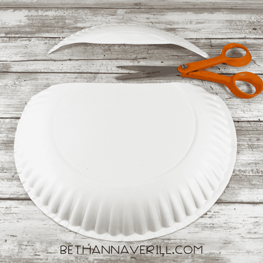 Image showing a paper plate folded and cut to form the base of the pot shape with scissors nearby.