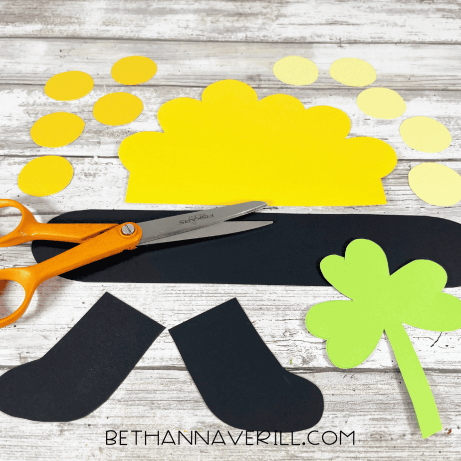 Image showing cardstock pieces cut out with pot, shamrock, and gold coin patterns along with cut yellow paper circles and black pot shapes.