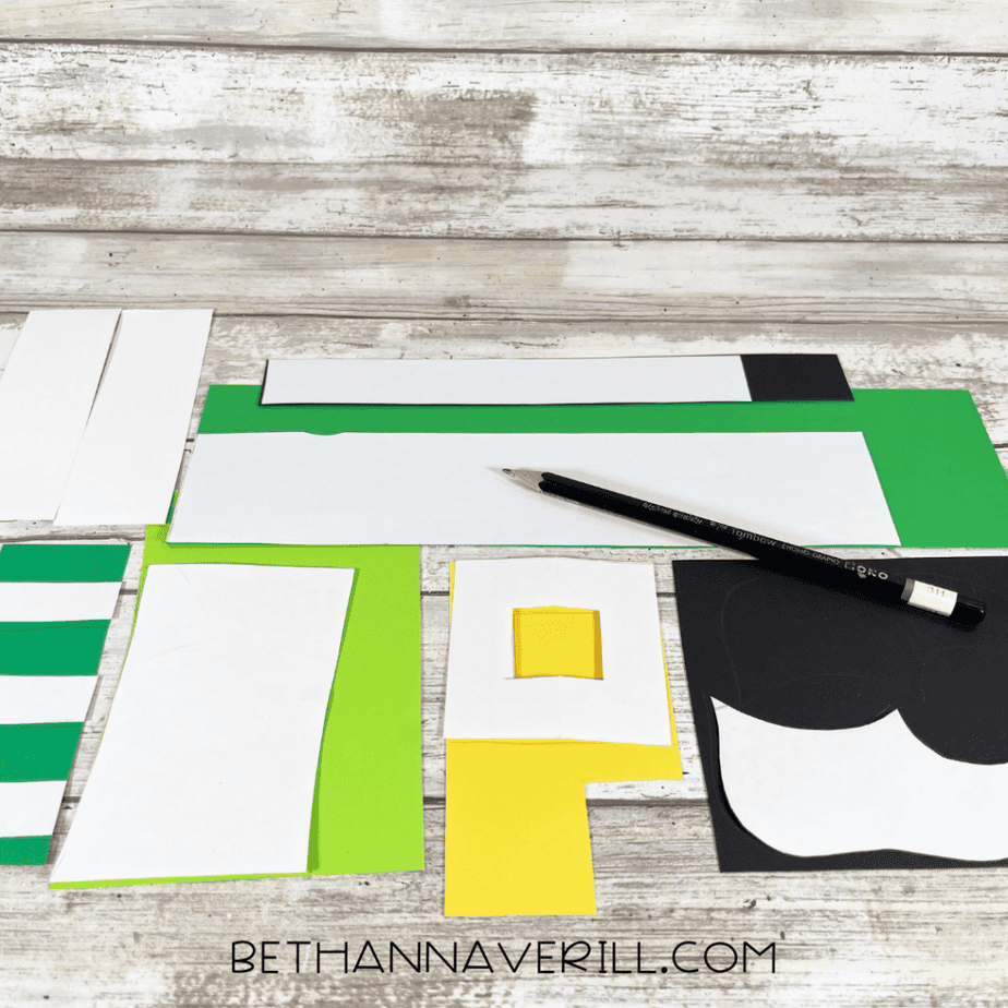 Printed paper templates and colored cardstock pieces arranged on a table with a pencil for tracing.