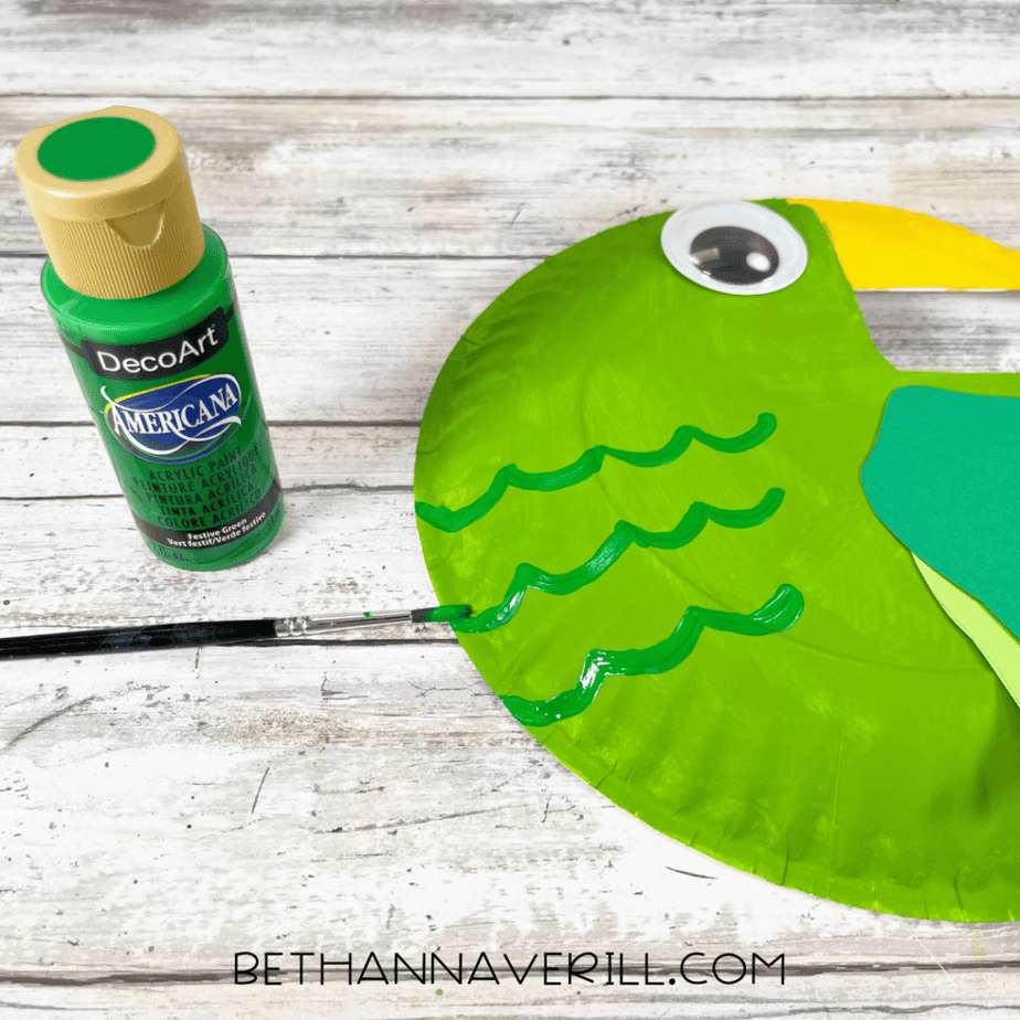 Green painted paper plate with wavy lines painted on it using green paint.