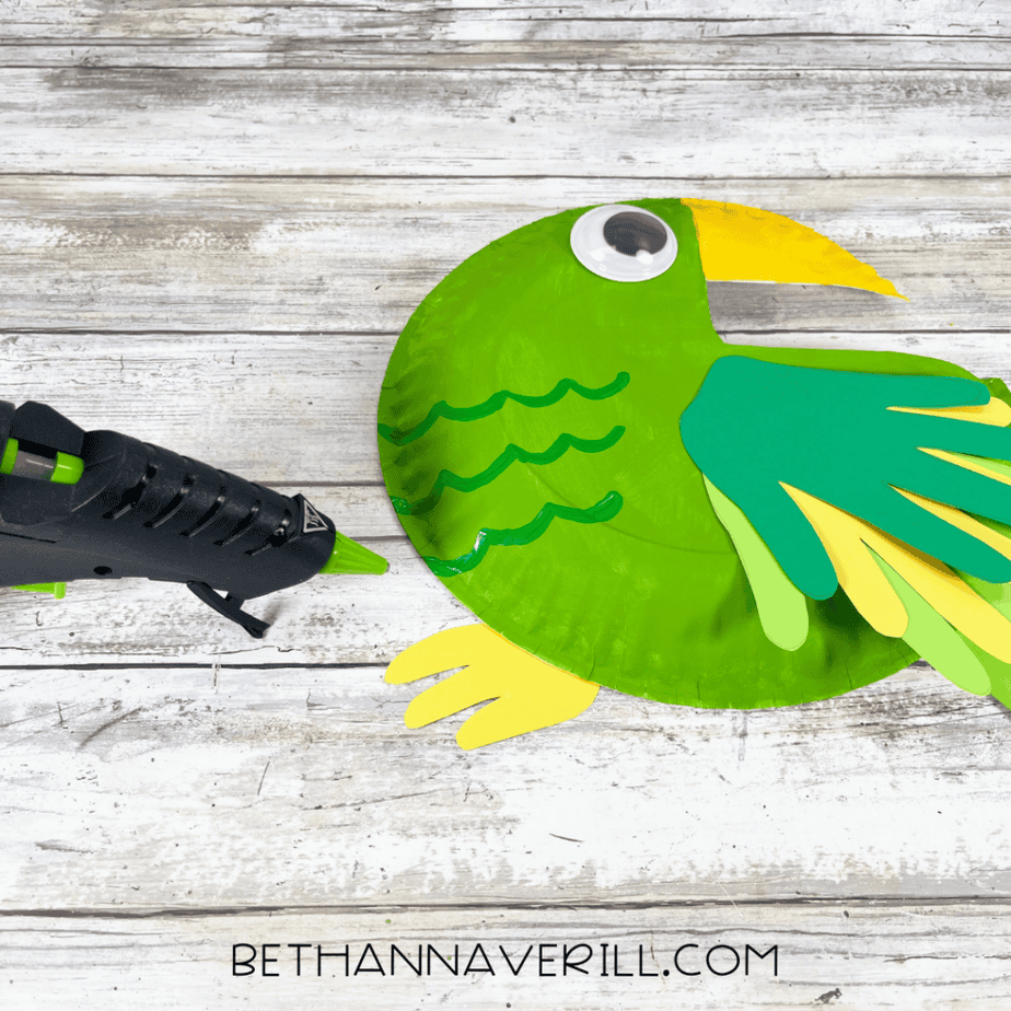 Cardstock foot being glued to the parrot paper plate craft