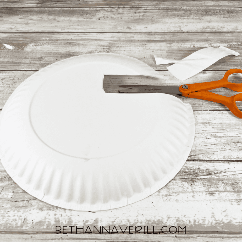 Paper plate with a section cut out using scissors, leaving a curved opening.