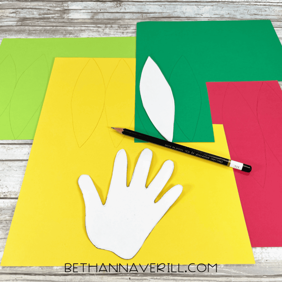 Paper pattern pieces traced onto green, yellow, and red cardstock with a pencil.