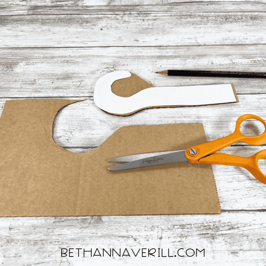 Hook pattern traced onto cardboard with scissors nearby.