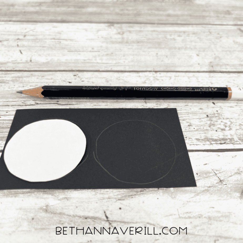 Two circles traced onto black cardstock using a pencil to create wheels for a popsicle stick school bus craft.