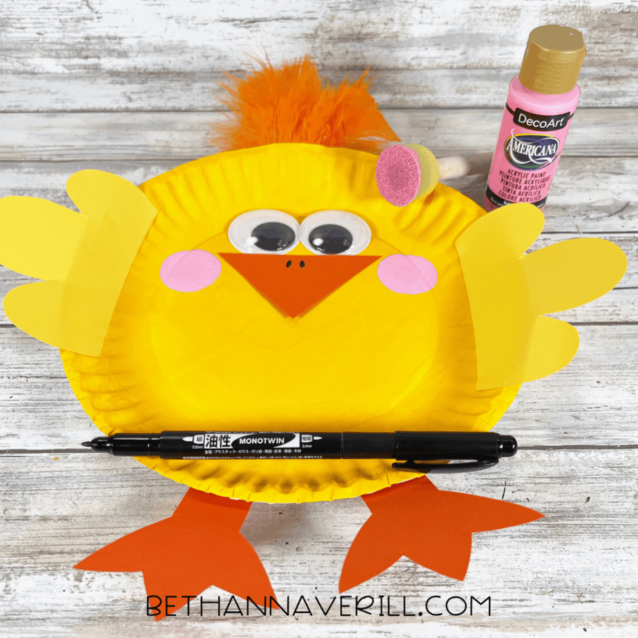 Pink circles being added as cheeks to the chick craft using pink paint and a foam dauber, with a black marker nearby.
