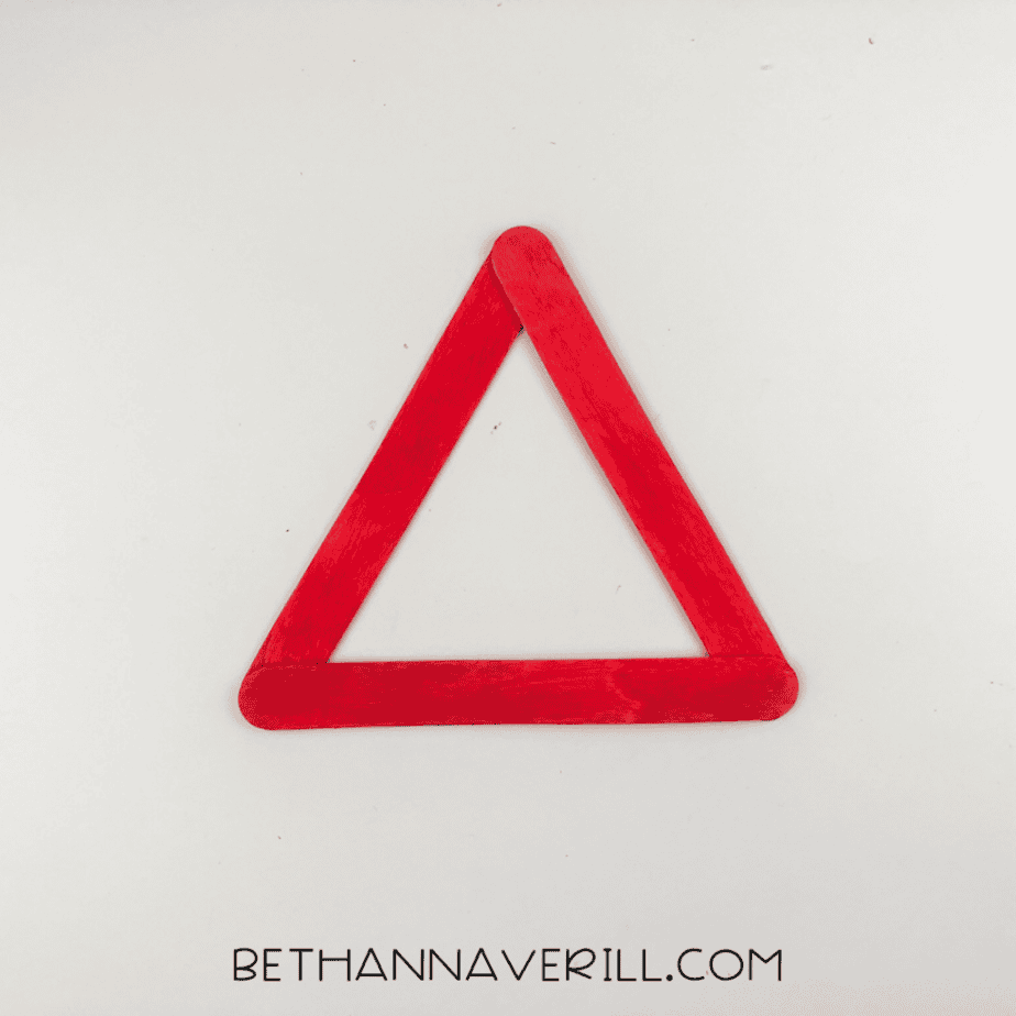 Three red popsicle sticks arranged in a triangle shape on a white background