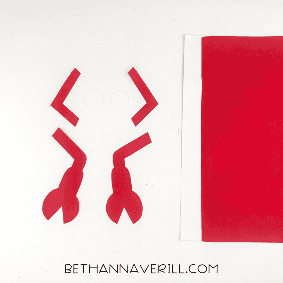 Red paper cutouts shaped like claws and legs beside colored paper sheets
