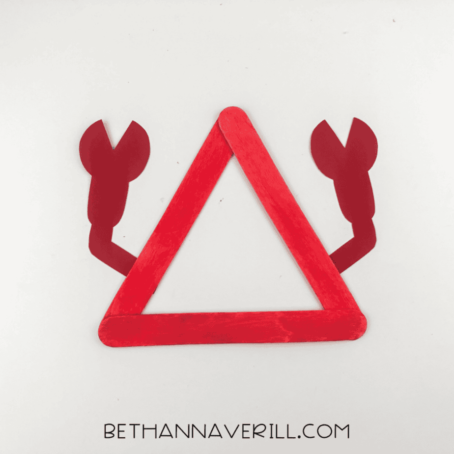 Triangle made from red popsicle sticks with two claw shapes attached on each side