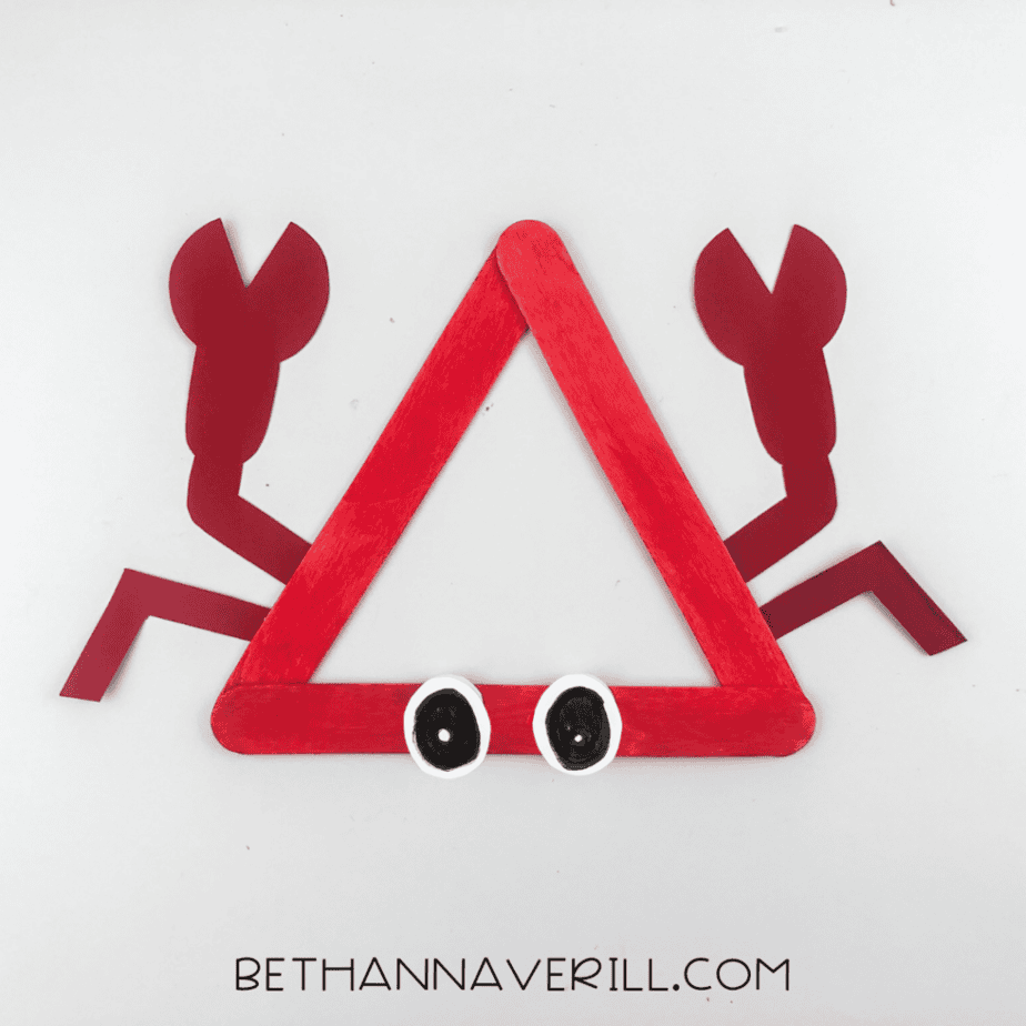 Red popsicle stick triangle craft with drawn eyes attached at the bottom