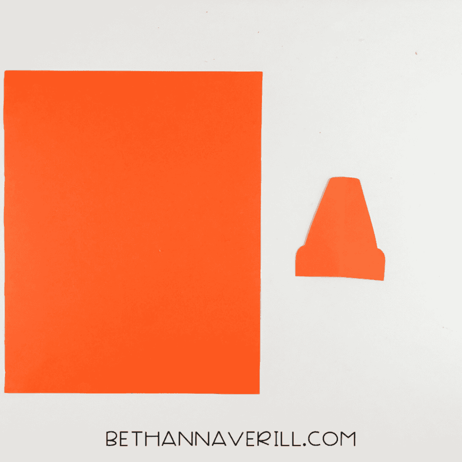 Square orange paper and a small cut orange paper shape on a white background