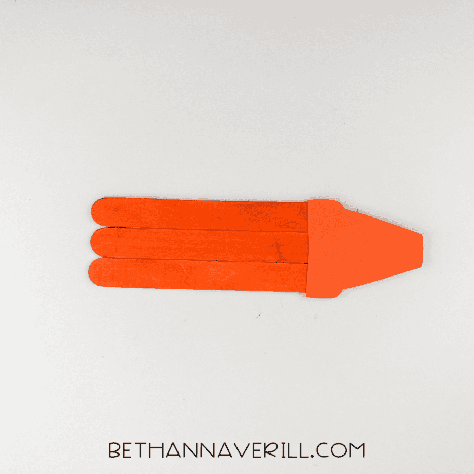 Three orange popsicle sticks glued together with a paper piece attached at one end