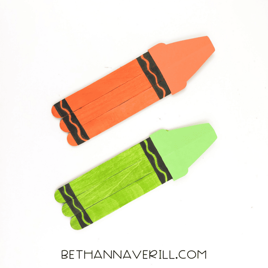 Two completed popsicle stick crafts painted orange and green with black wavy lines