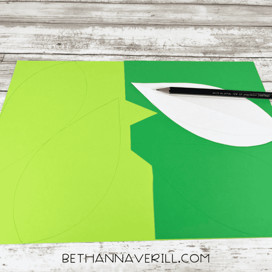 Leaf shapes traced onto green paper using a template and pencil.