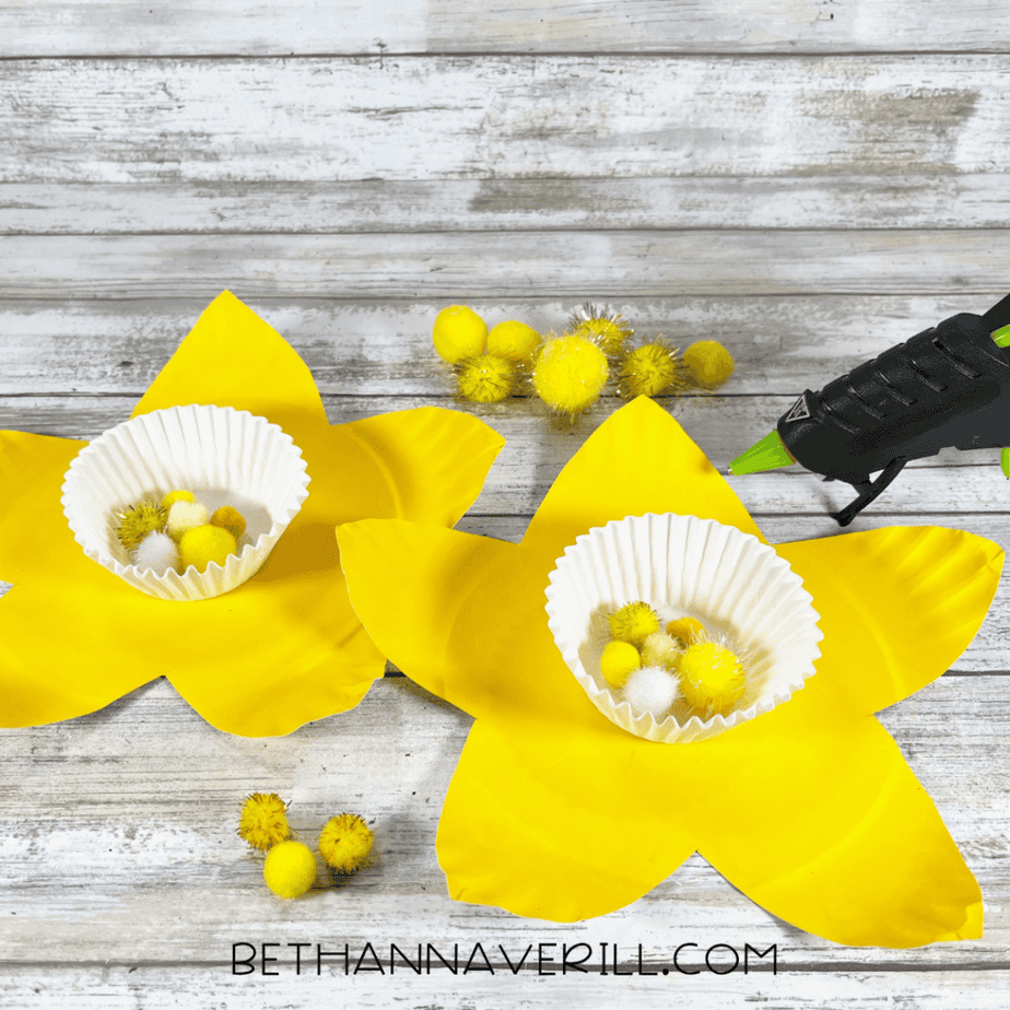 Pom poms being added into cupcake liners in the center of the flower shapes.