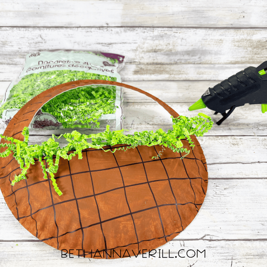 Paper plate basket with green shredded paper glued along the top edge