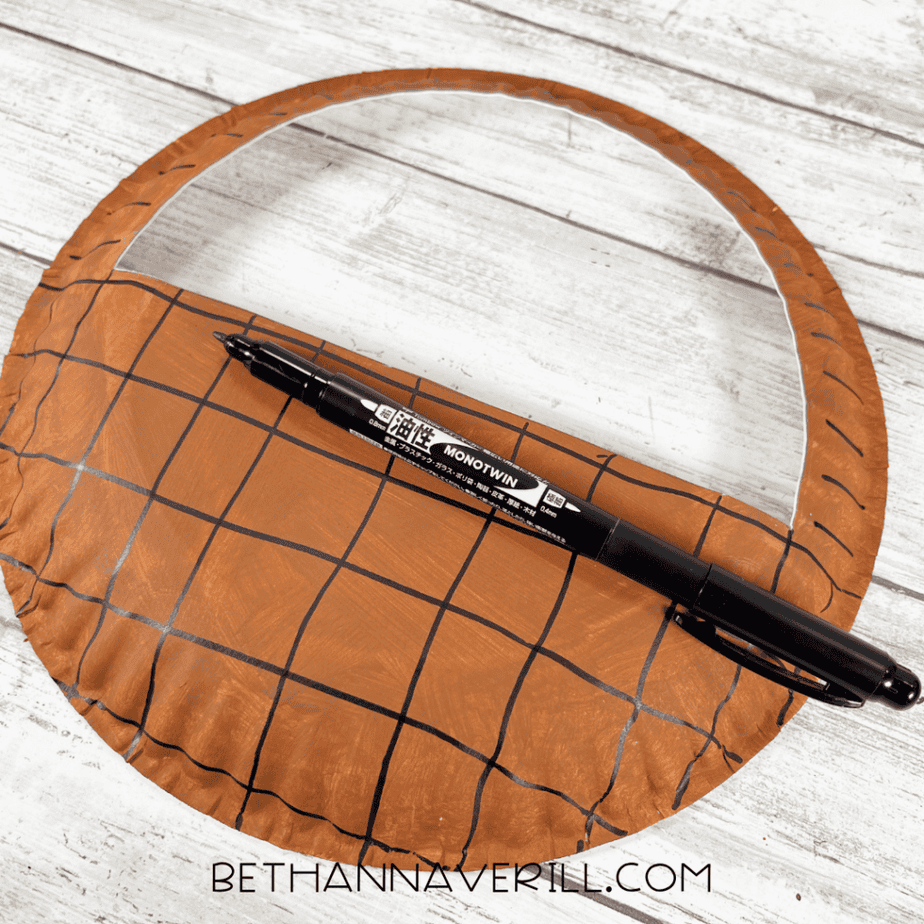 Paper plate basket with handle drawn in black marker to create a woven pattern