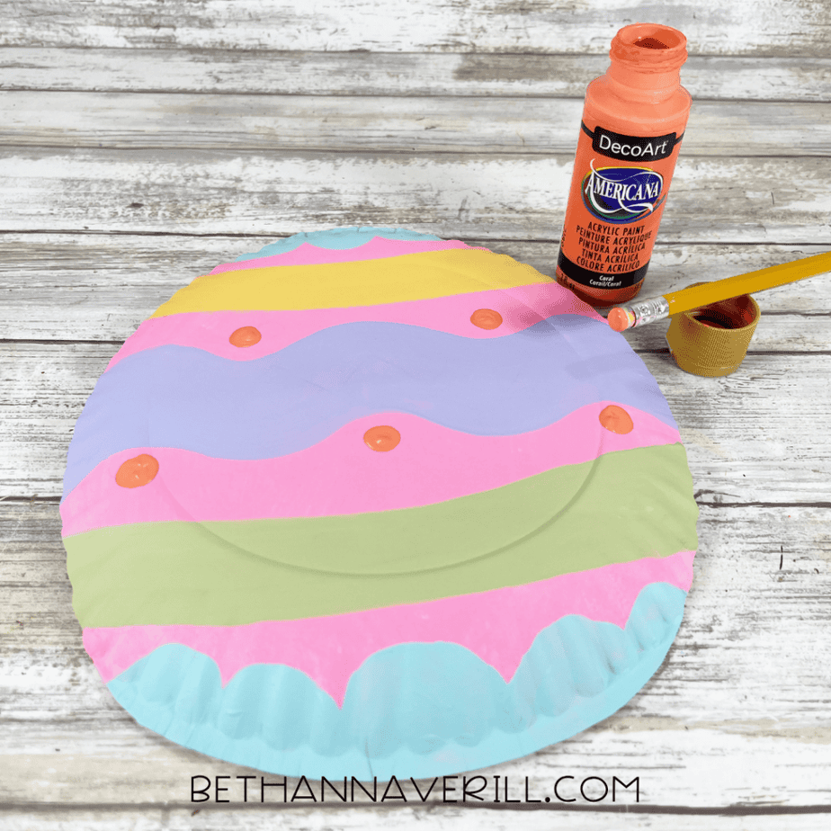 The striped plate with small orange dots being added using paint.