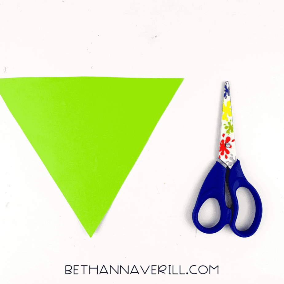 Green triangle paper cut to fit inside a popsicle stick triangle frame for a Frankenstein craft.