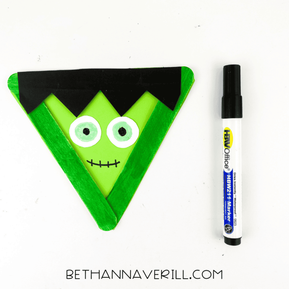 Frankenstein popsicle stick craft with stitched mouth drawn using a black marker.