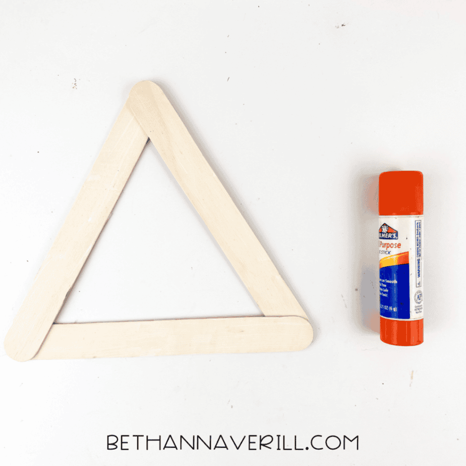 Three craft sticks glued together in a triangle shape to form the base of a ghost popsicle stick craft.