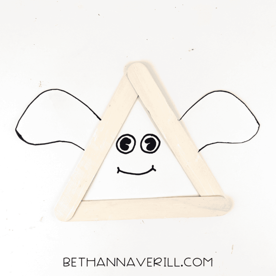 Completed ghost popsicle stick craft with triangle craft stick frame and paper ghost arms.