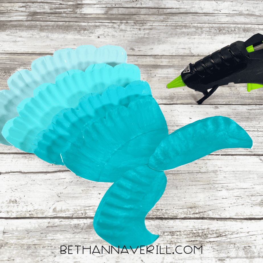 Layered painted paper plate pieces forming the shape of a mermaid tail.