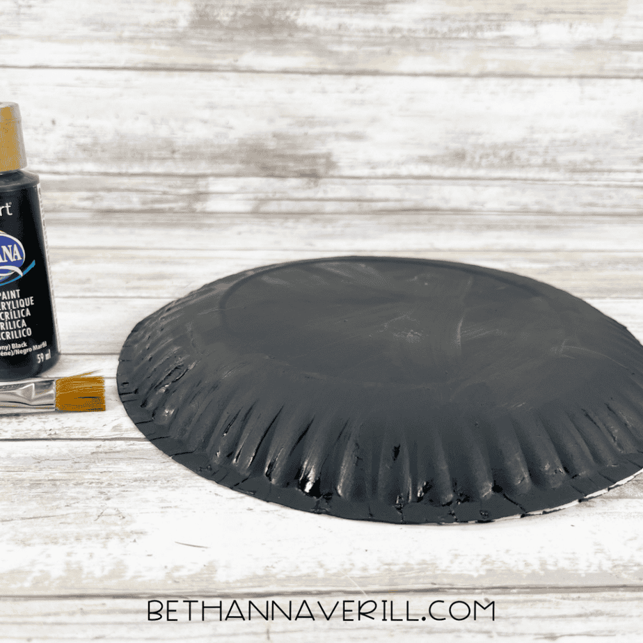 Paper plate painted black for pirate hat paper plate craft.