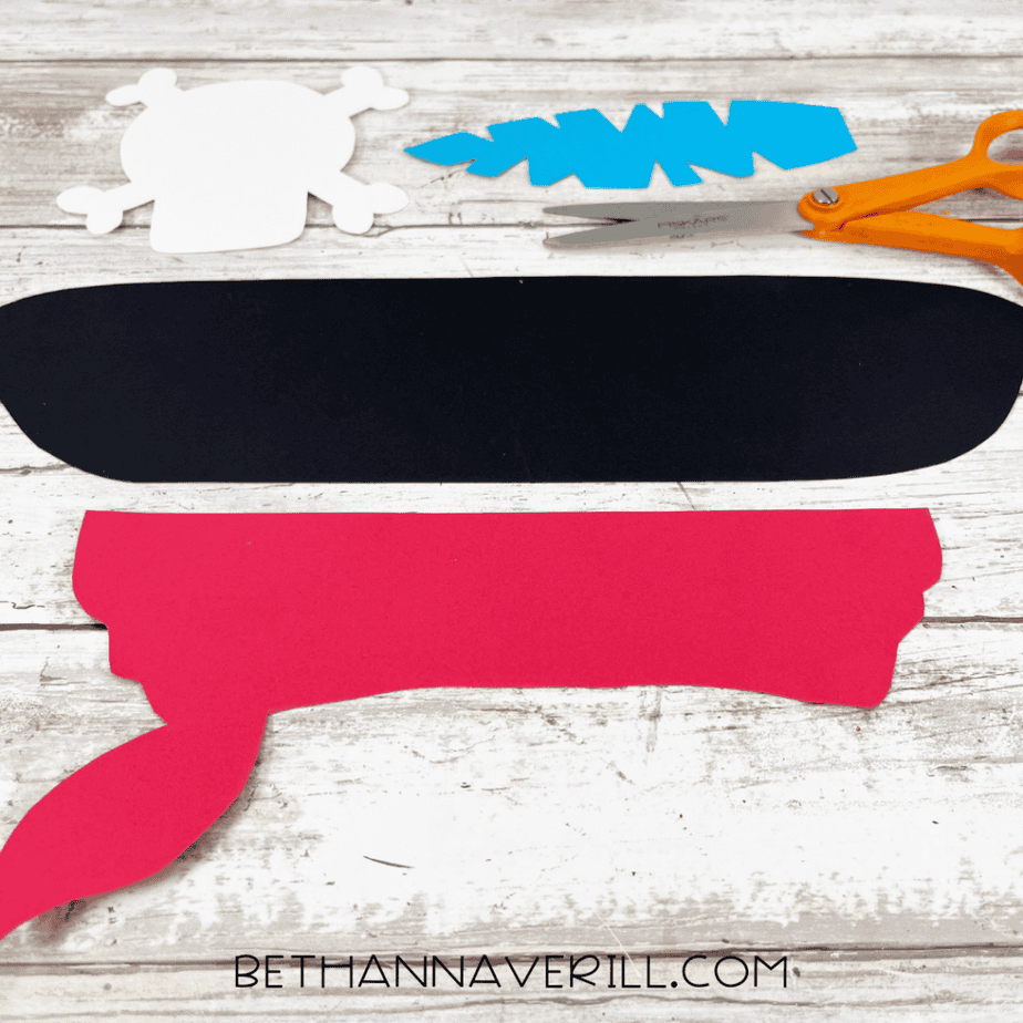 Pirate hat craft pieces including skull template, feather, and red bandana cut from cardstock.