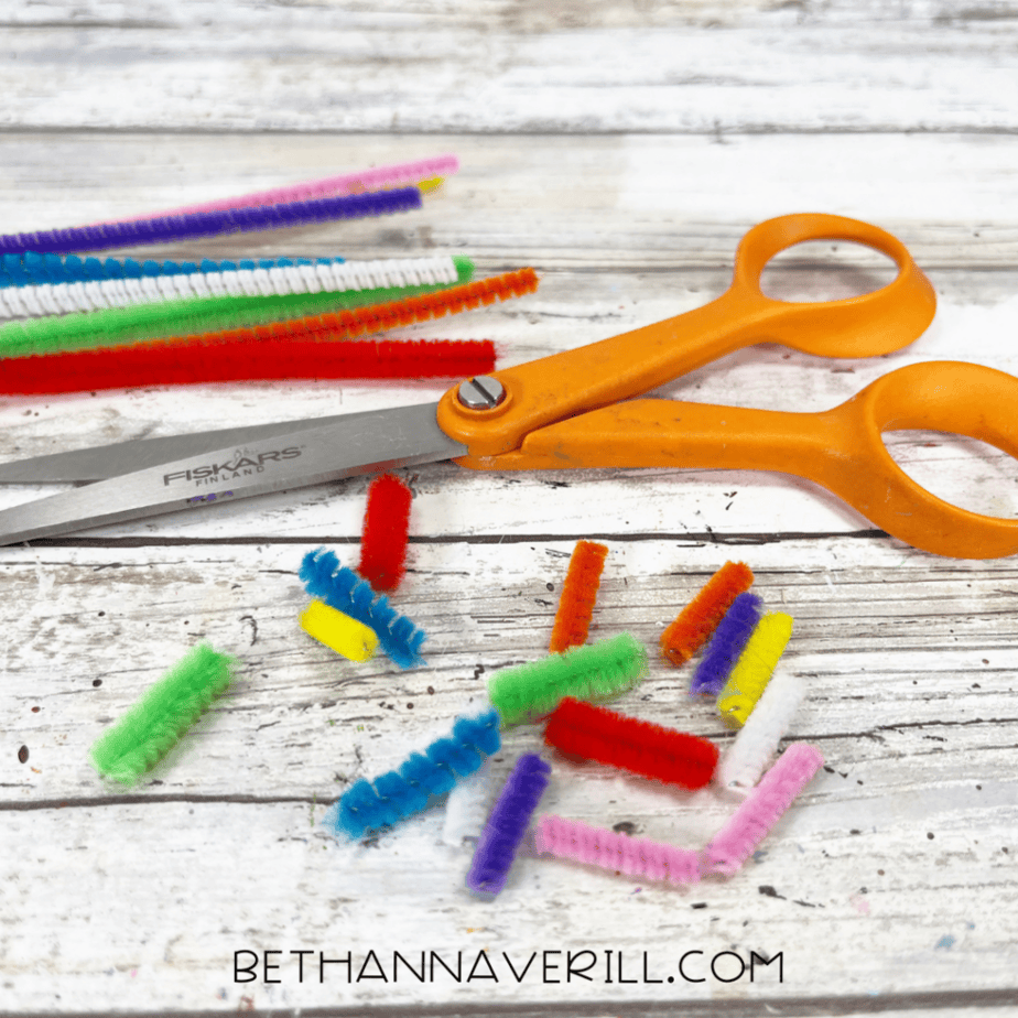 Small cut pieces of multicolored pipe cleaners scattered next to scissors.