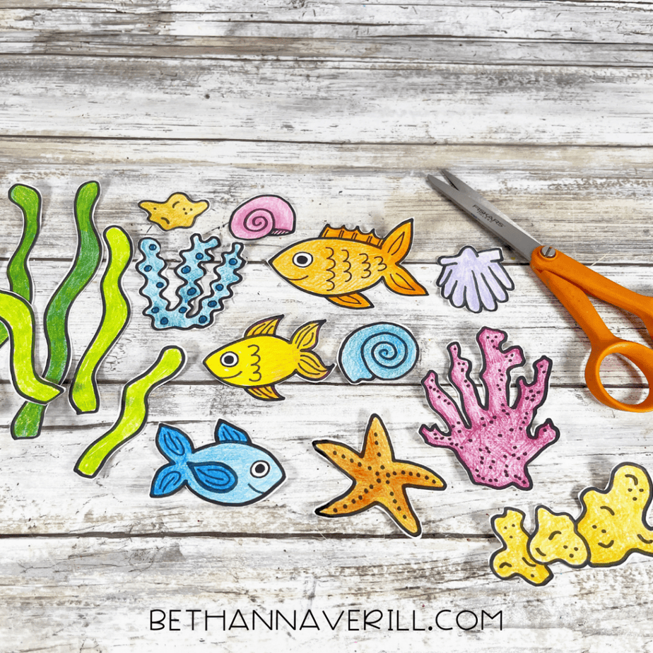 Cut-out colored ocean shapes spread on a surface with scissors nearby.