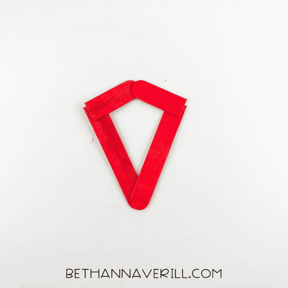 The red popsicle stick pieces glued together into a triangular strawberry frame.