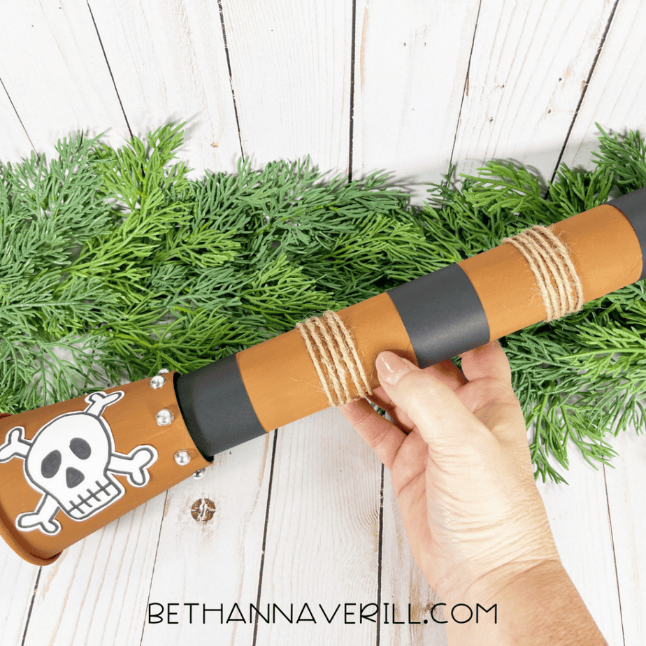 The finished pirate telescope craft held in a hand with greenery in the background.