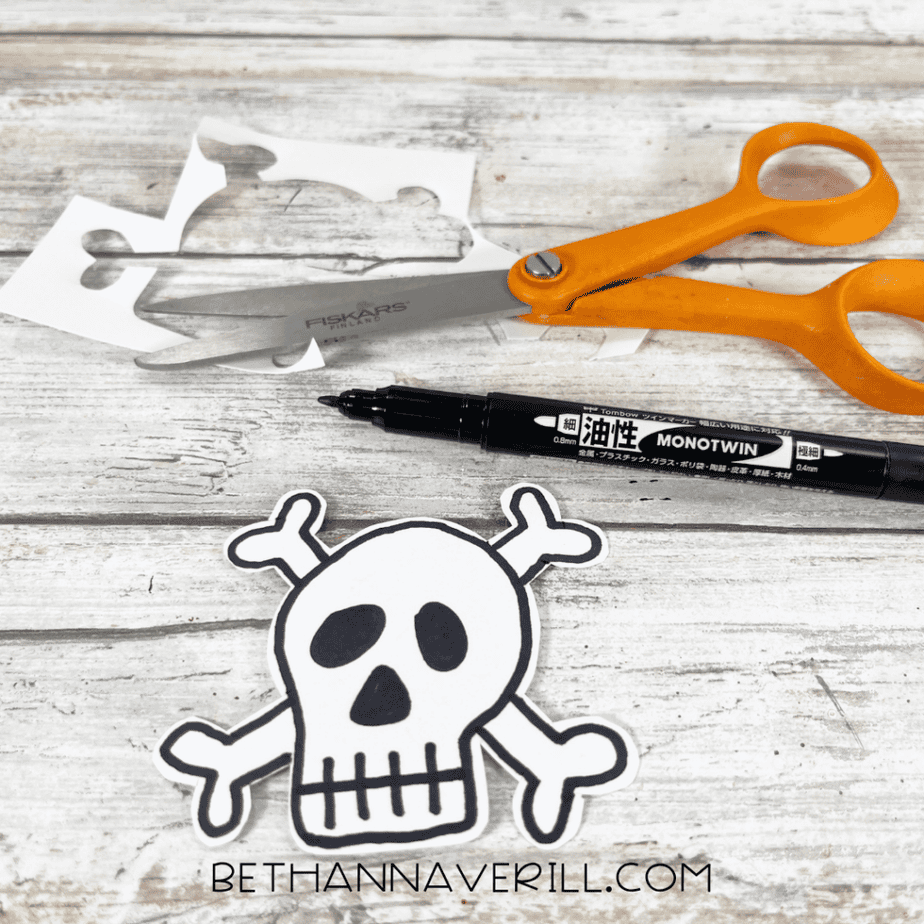 The skull-and-crossbones cut out and outlined in black marker next to scissors and marker scraps.