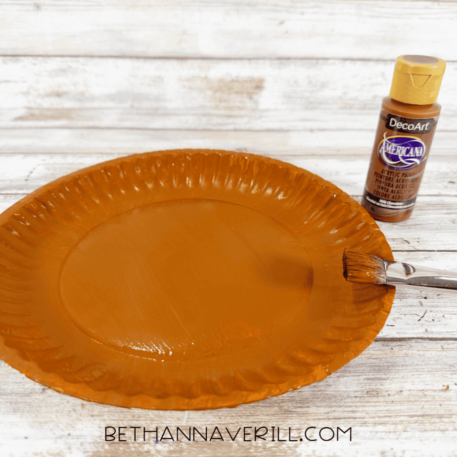 Paper plate painted brown with acrylic paint using a flat paintbrush.