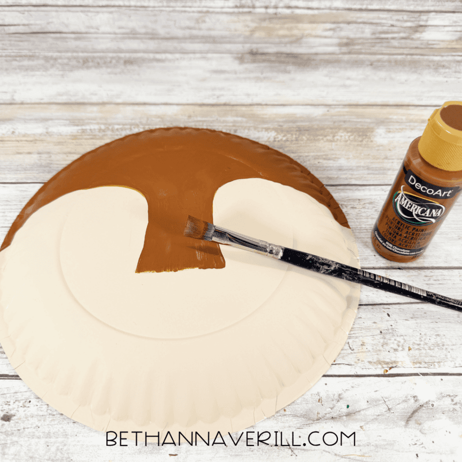 Cream paper plate with the upper center section painted brown, leaving two large cream face areas unpainted.