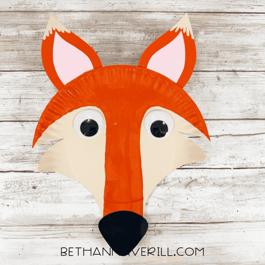 Finished paper plate fox craft with orange fur, cream cheeks, large googly eyes, pointed orange and pink ears and a black nose.